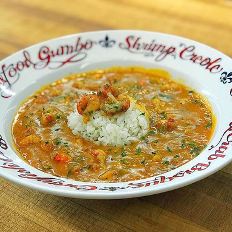 A bowl of shrimp and crawfish étouffée with rice, garnished with parsley, on a white plate.