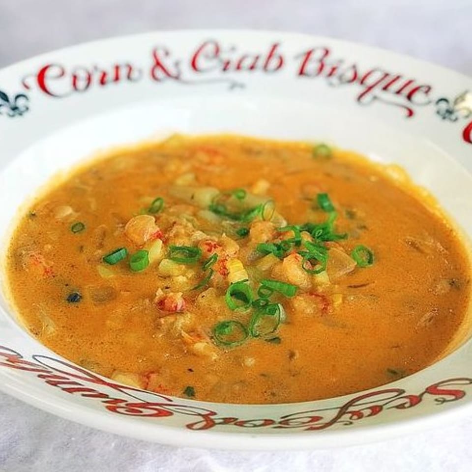 A bowl of Corn & Crab Bisque, garnished with green onions, from Taylor's Meat Company.