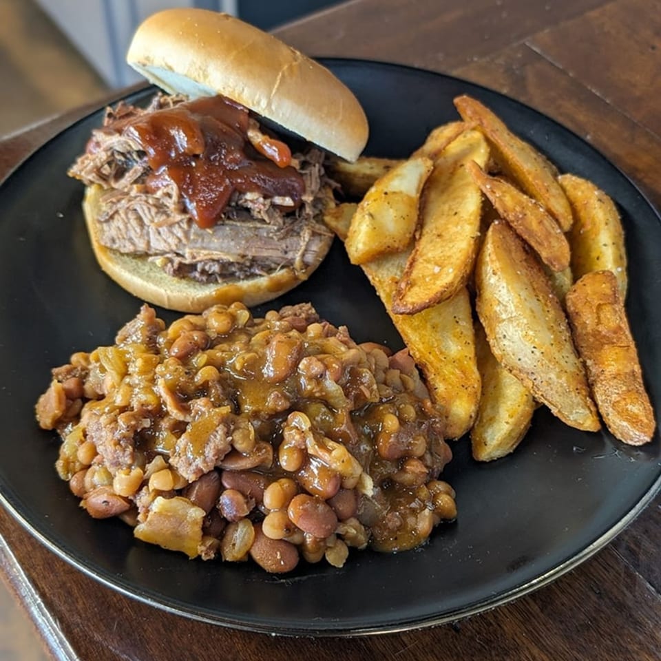 Taylor's Meat Company BBQ plate with a pulled pork sandwich, baked beans, and potato wedges.